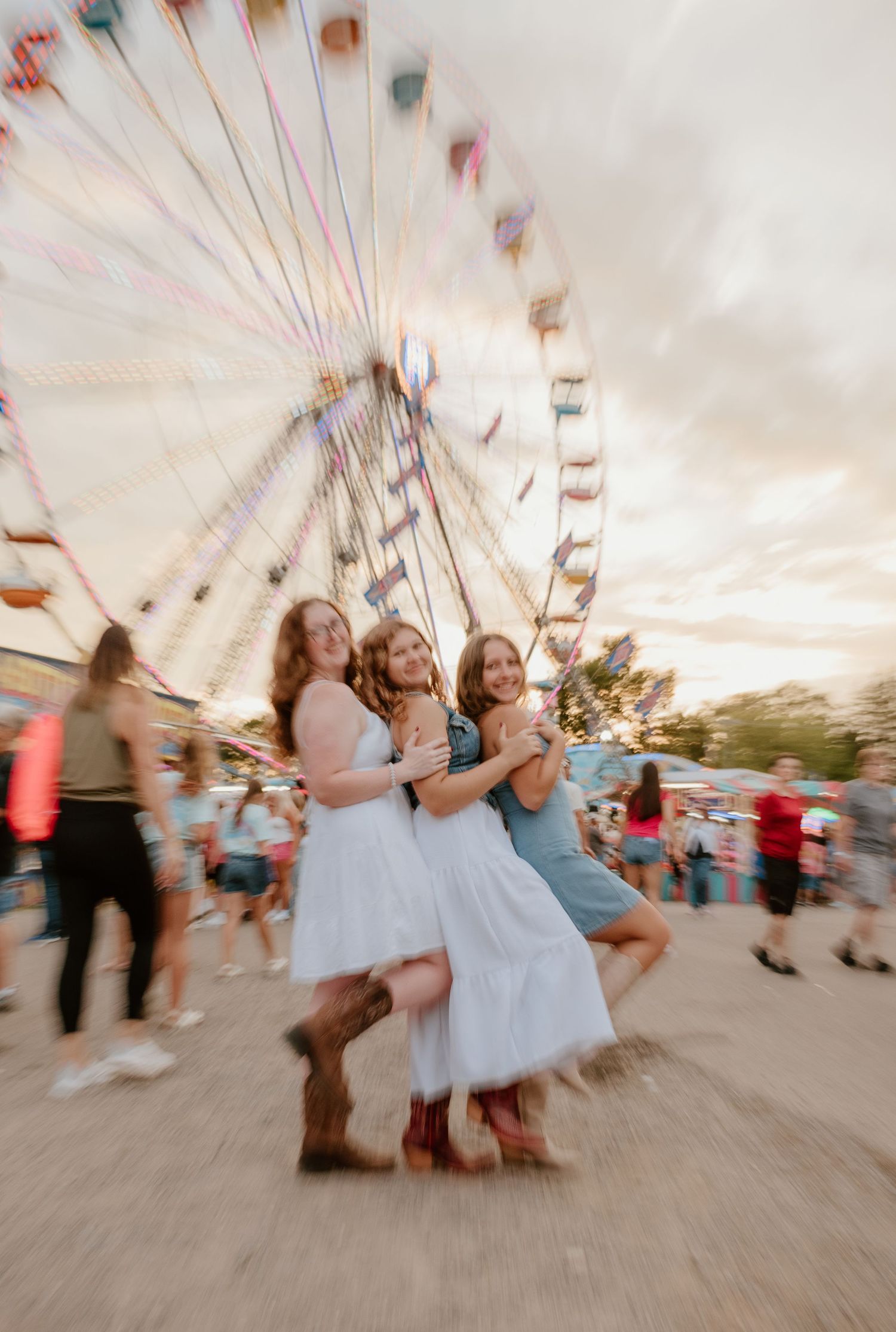 Motion blur captures the energy and movement of people enjoying carnival rides at a fairground during sunset.