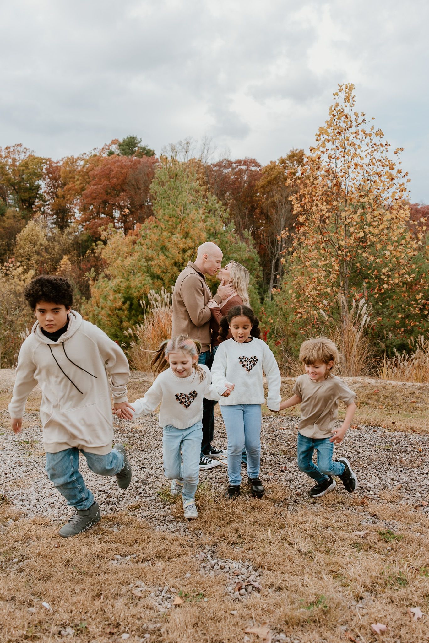 Children running and playing together on a fall day with autumn foliage in the background.