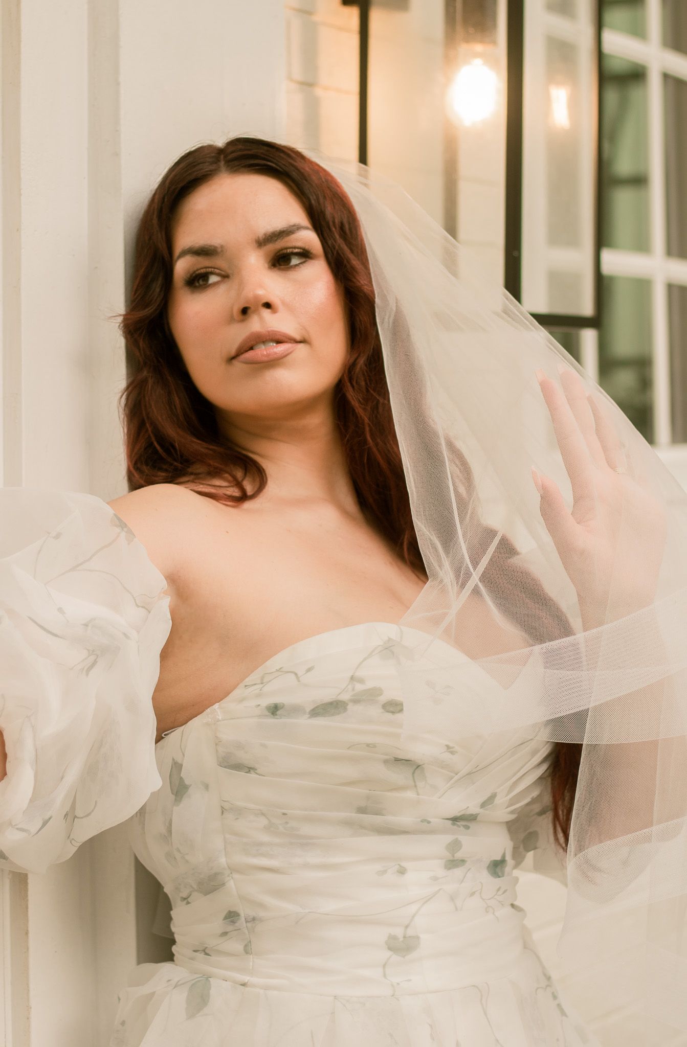 Ethereal bridal portrait featuring flowing tulle veil and romantic white gown against a light-filled backdrop.