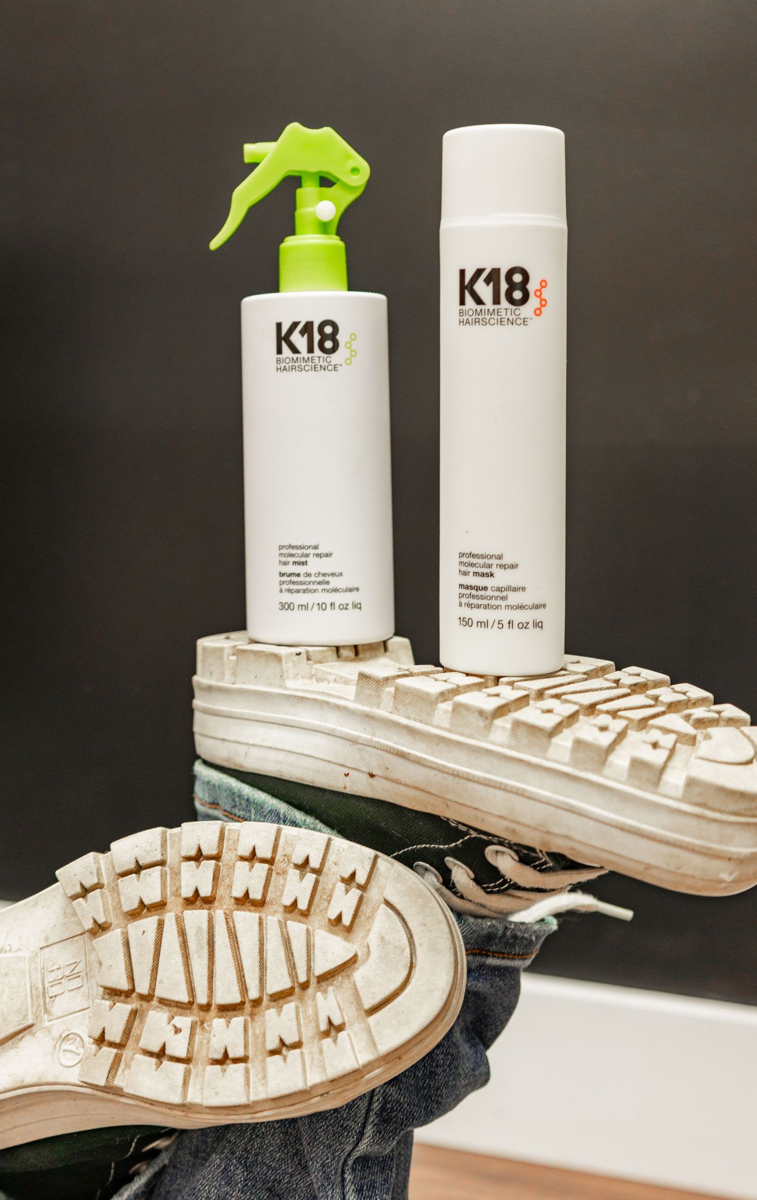 White hair product bottles displayed with wooden shoe forms arranged in a stylish retail presentation.
