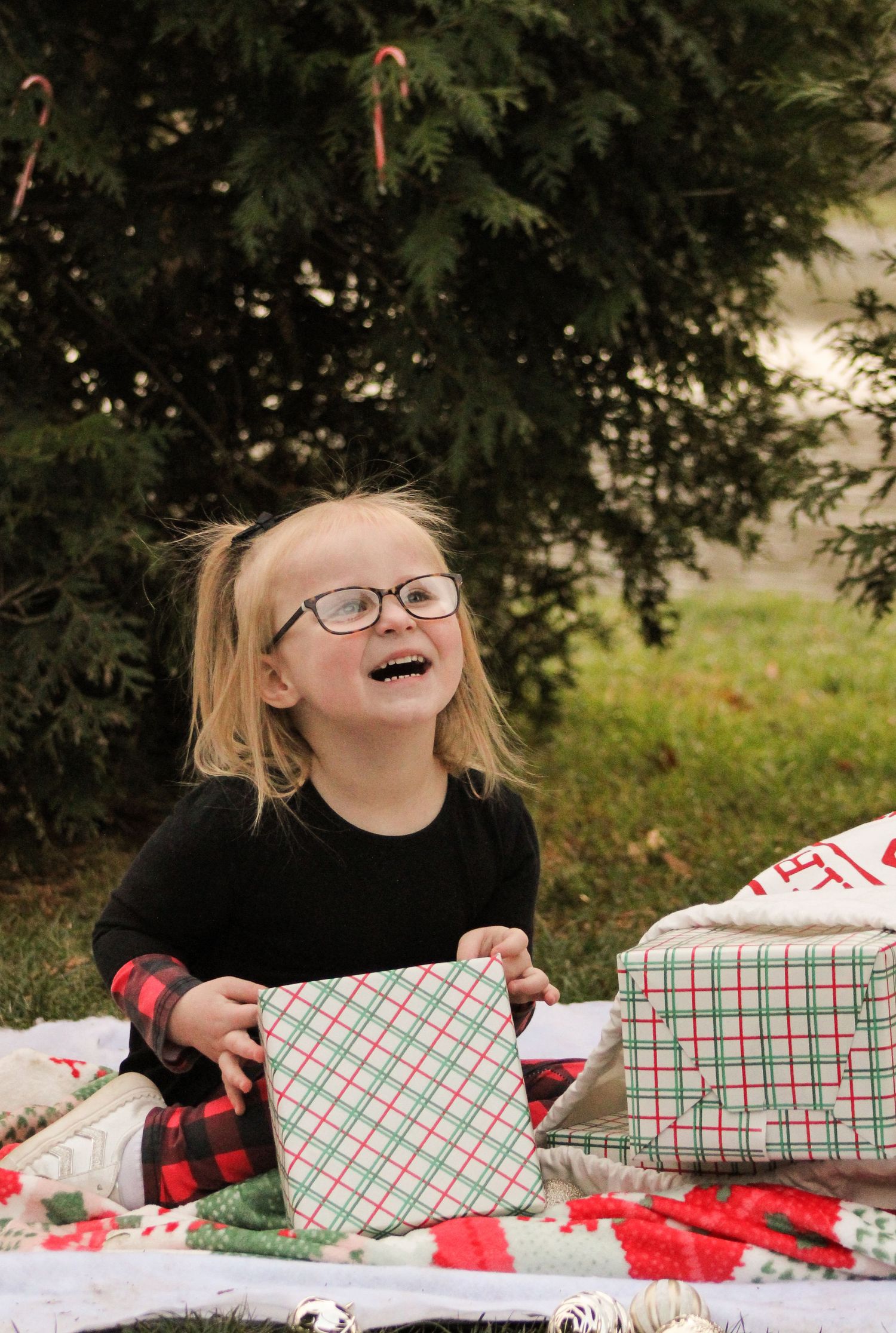 A sequence of photos showing someone joyfully opening Christmas presents at a table with red and green plaid wrapping paper.