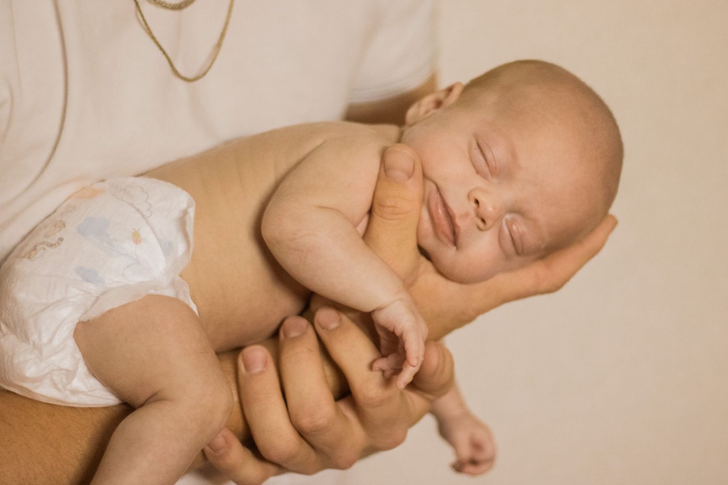 Peaceful sleeping baby wearing white clothing lies on soft cream-colored bedding in a collage of six photos.