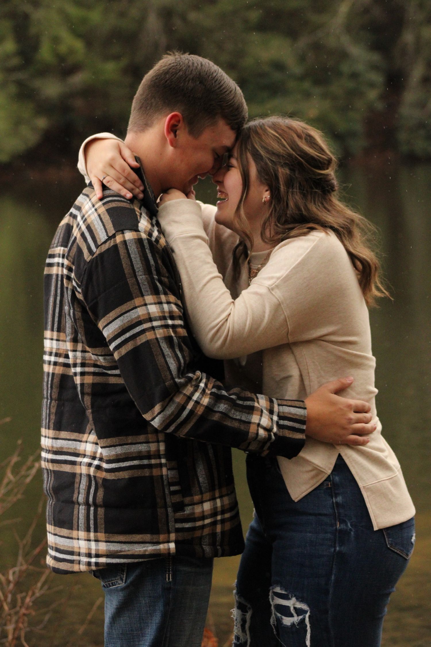 A series of intimate moments captured between a couple in plaid and cream colored sweaters by a lake.