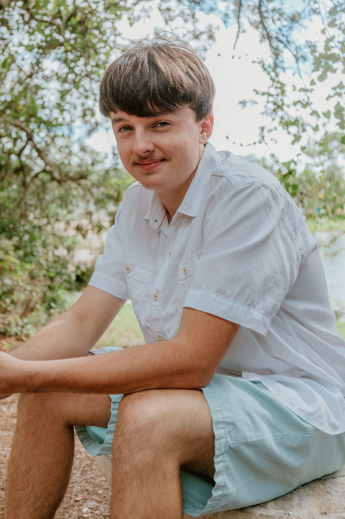 Casual outdoor portrait series showing someone seated wearing a white shirt and mint shorts.