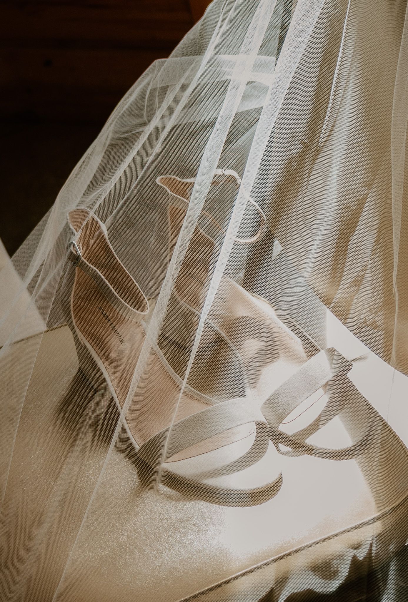 Close-up view of delicate white tulle wedding veil fabric draped over a textured surface in soft natural light.