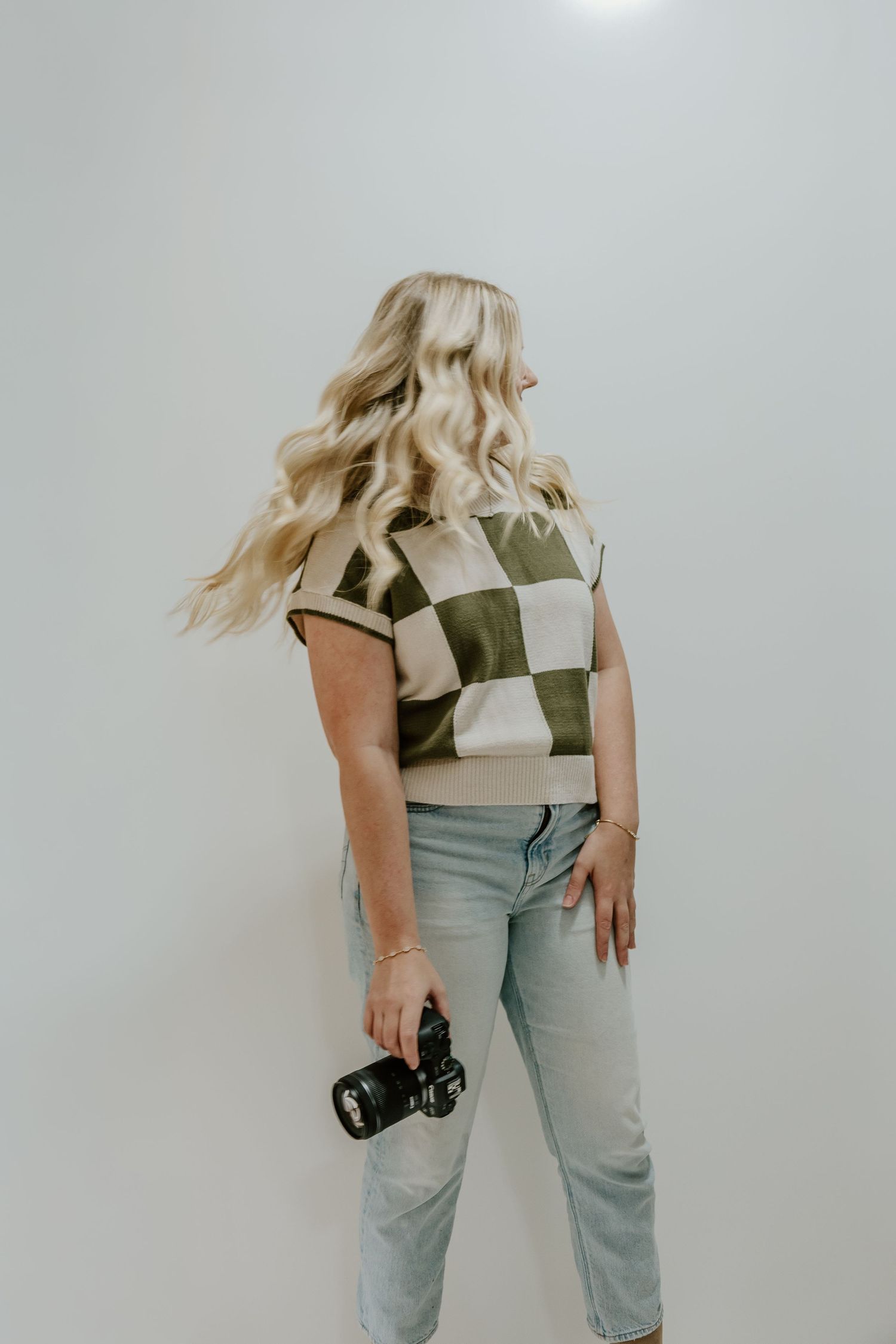 A person in a green top and light jeans dances and moves dynamically against a white background.