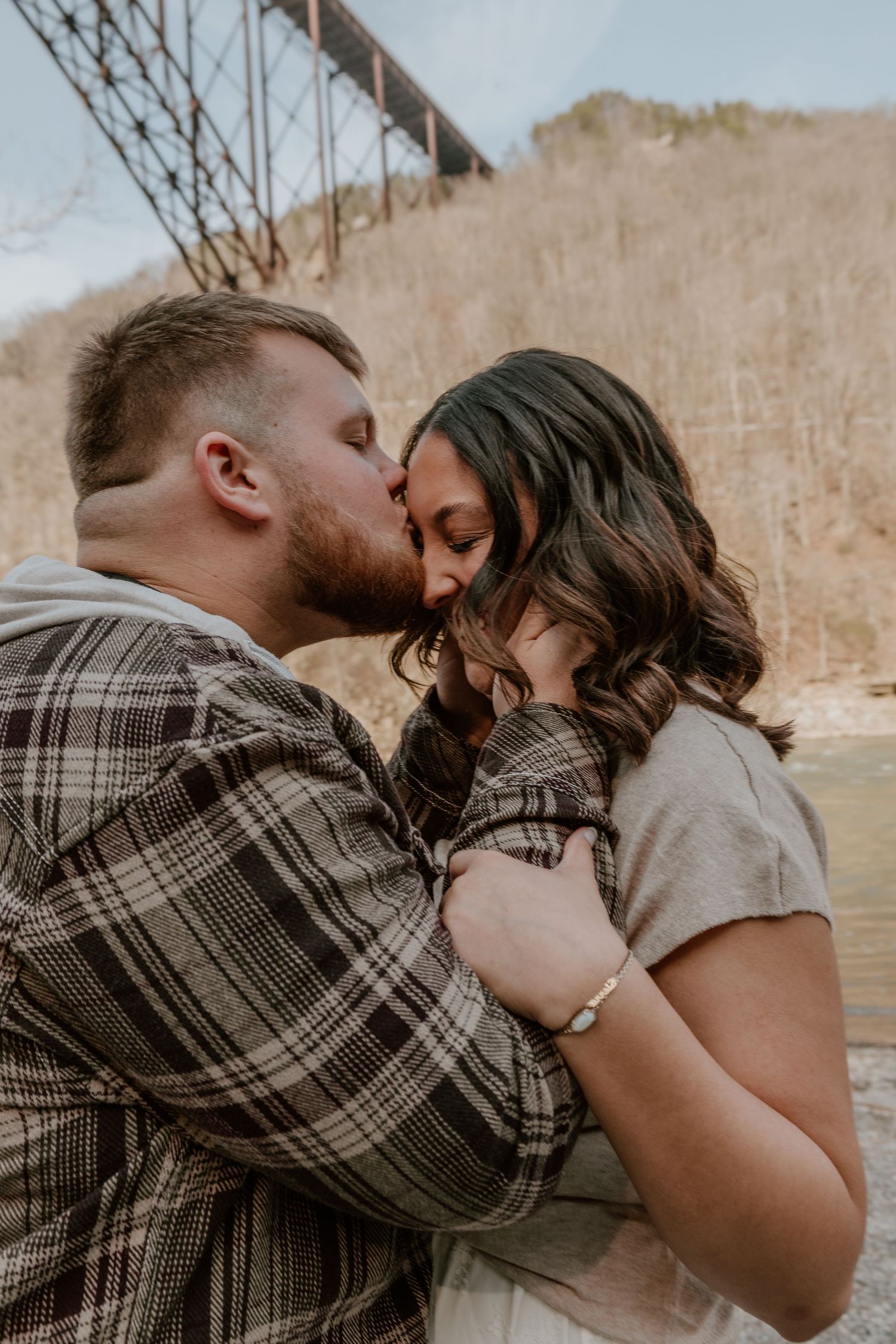 A romantic couple embraces and shares an intimate moment in a natural outdoor setting during golden hour.