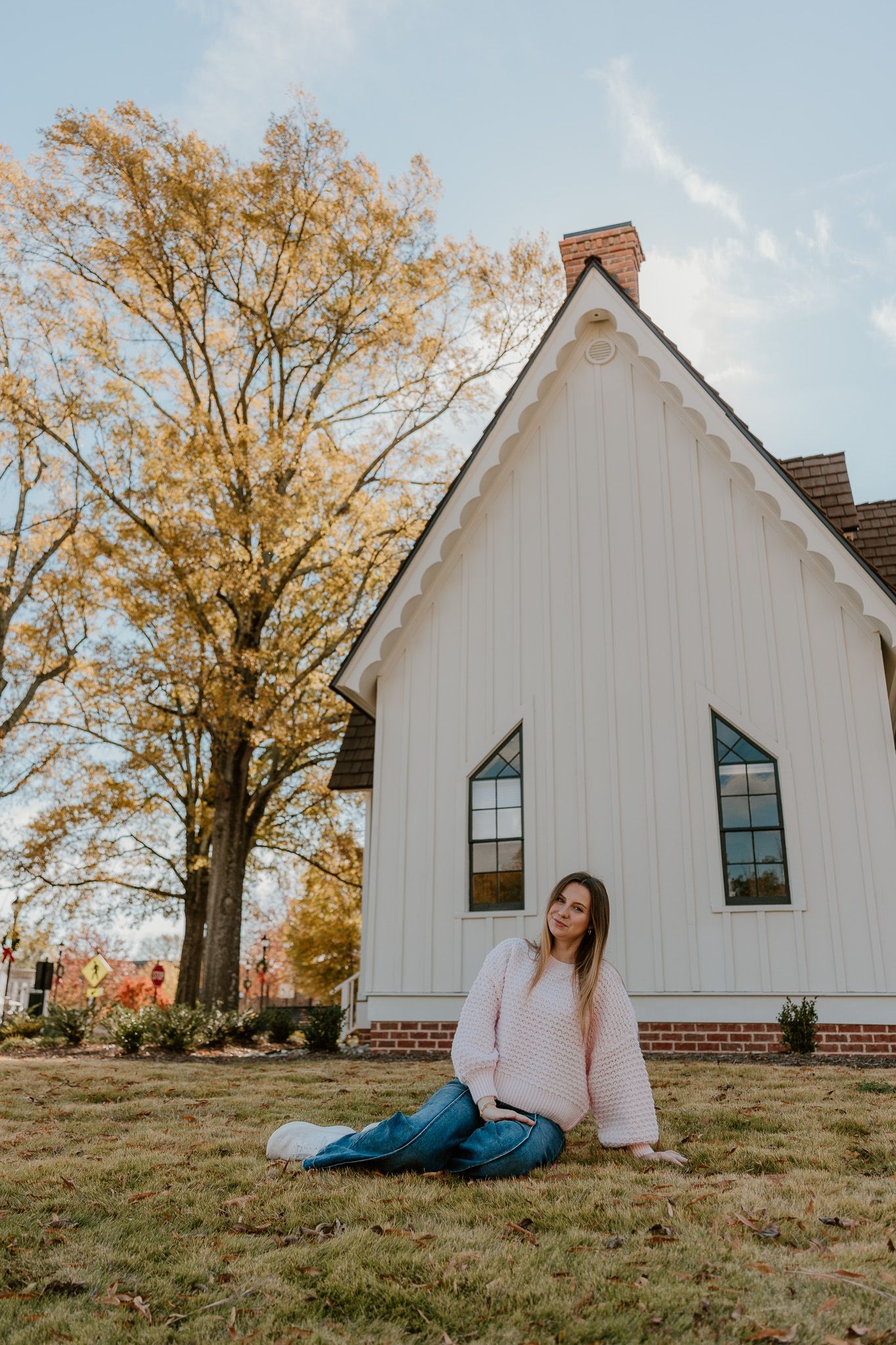 A series of portraits in front of a white chapel building with autumn trees in the background.