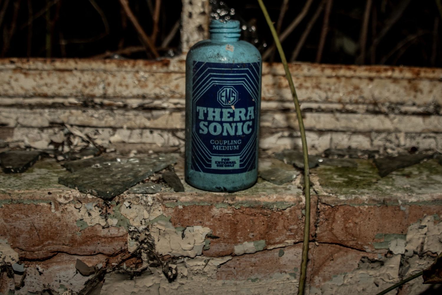 Blue TheraSonic bottle sitting on a cracked, weathered brick ledge in an abandoned building.  amman valley maternity hospital