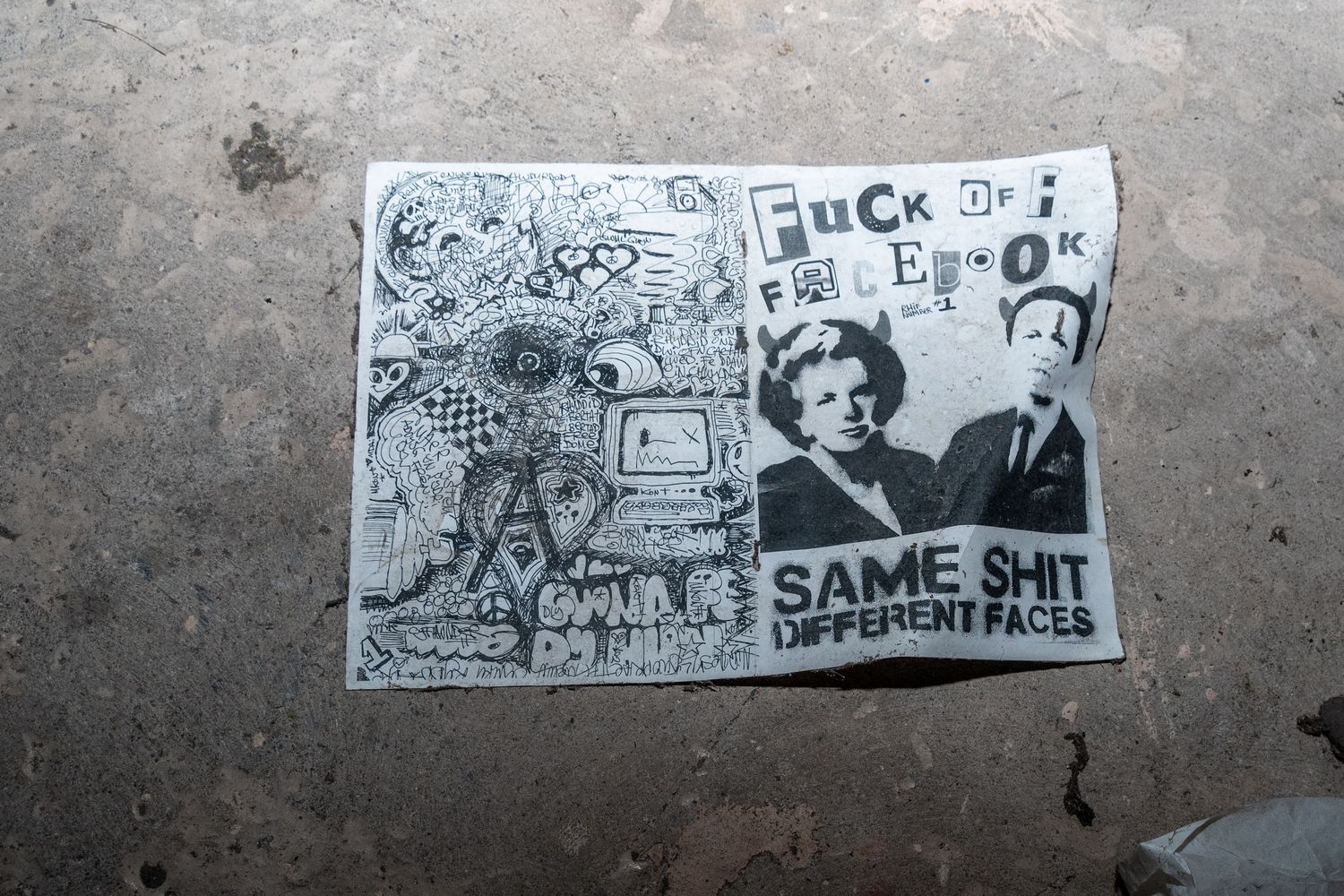 Black-and-white stencil-style graffiti poster on a concrete wall featuring text and illustrated faces. ash olion photo. spin bowling cardiff