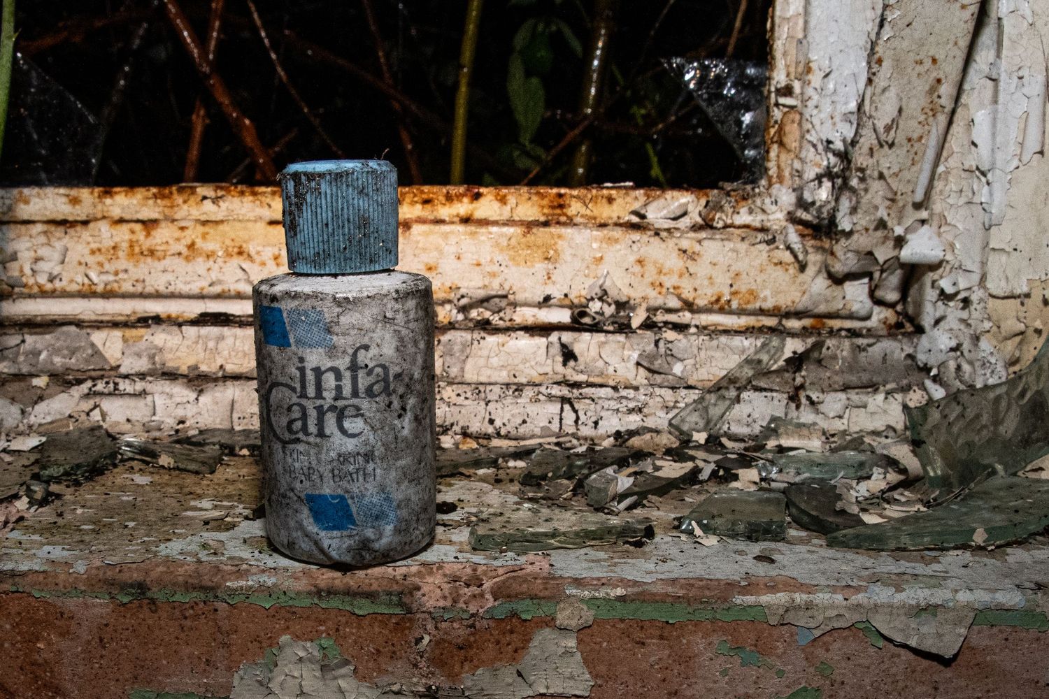 Dust-covered plastic bottle sitting on a decayed windowsill inside an abandoned building. amman valley maternity hospital ash olion photo