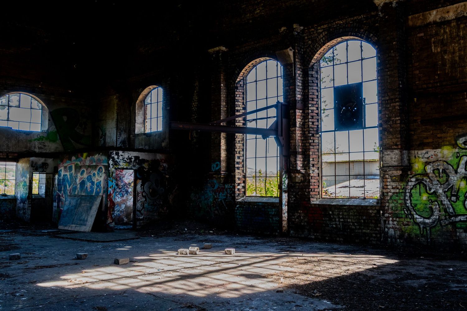 Sunlight casting grid-like window shadows across the dusty floor of an abandoned industrial hall. ash olion photography. welsh coalfield.