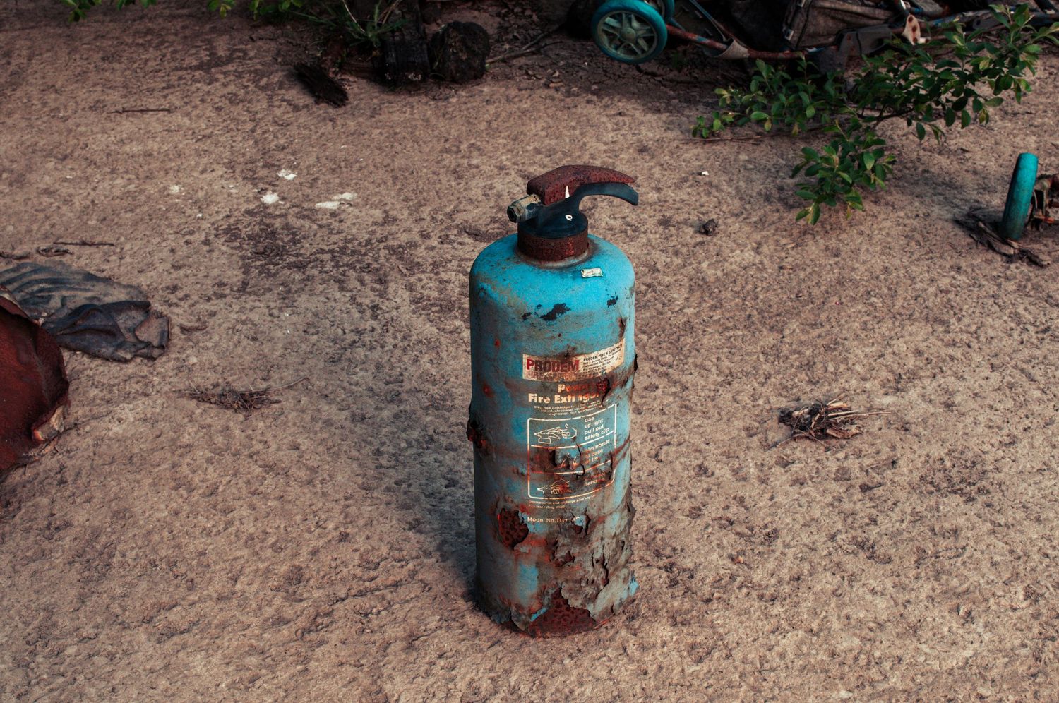 Old rusted gas cylinder standing alone on cracked, overgrown ground in an abandoned site. cwm coke works beddau wales.