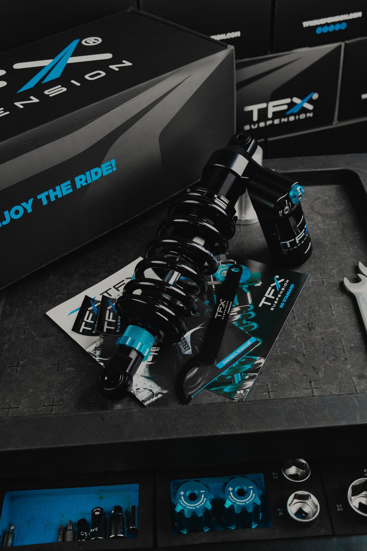 Close-up product shots of black and turquoise TFX cycling components displayed against dark background.