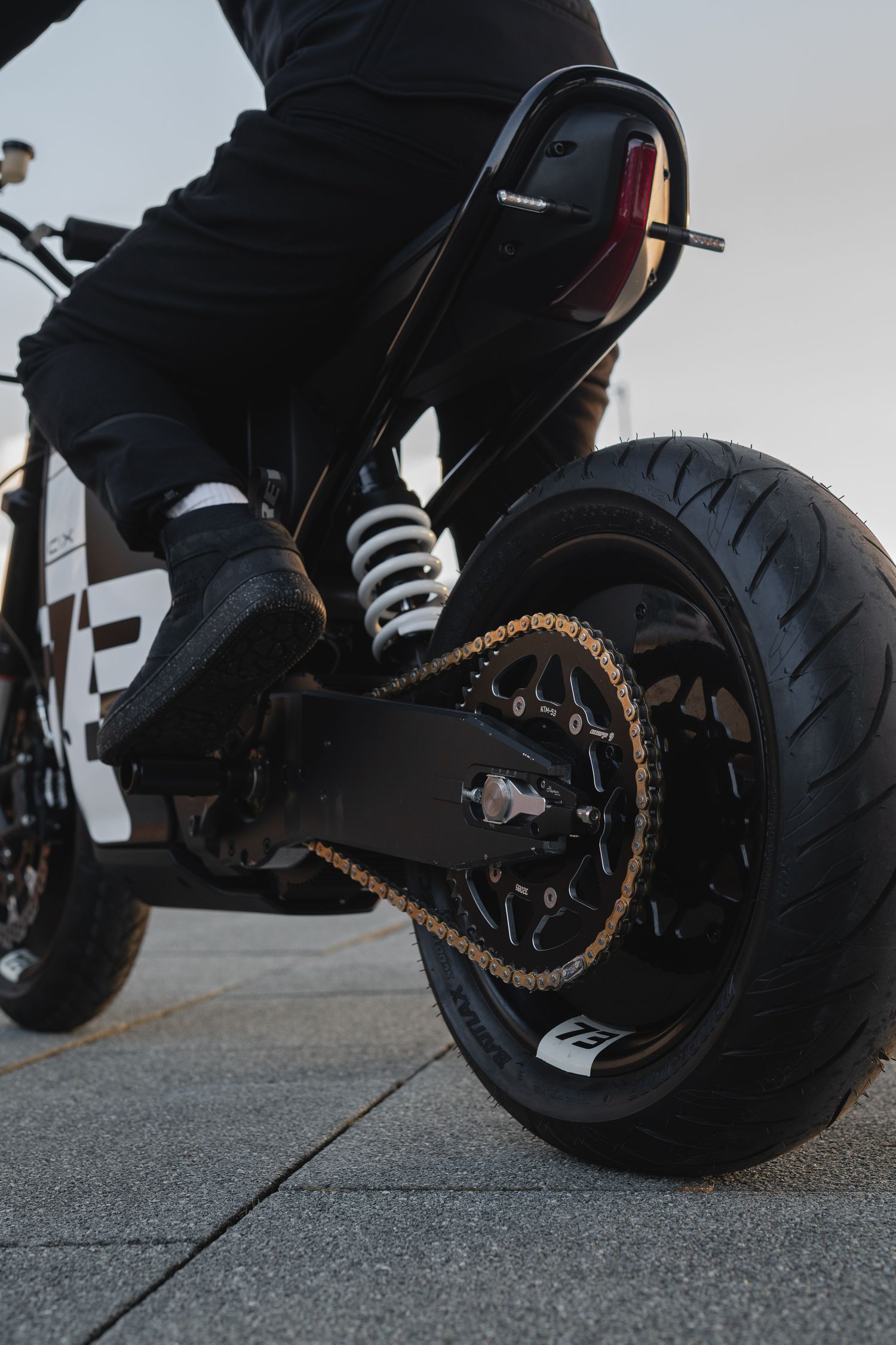 Low-angle view of motorcycle tires with custom black and gold chain.