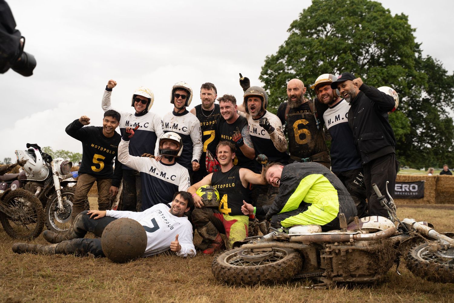 Group of motorcyclists taking a break on a hillside during an outdoor event.