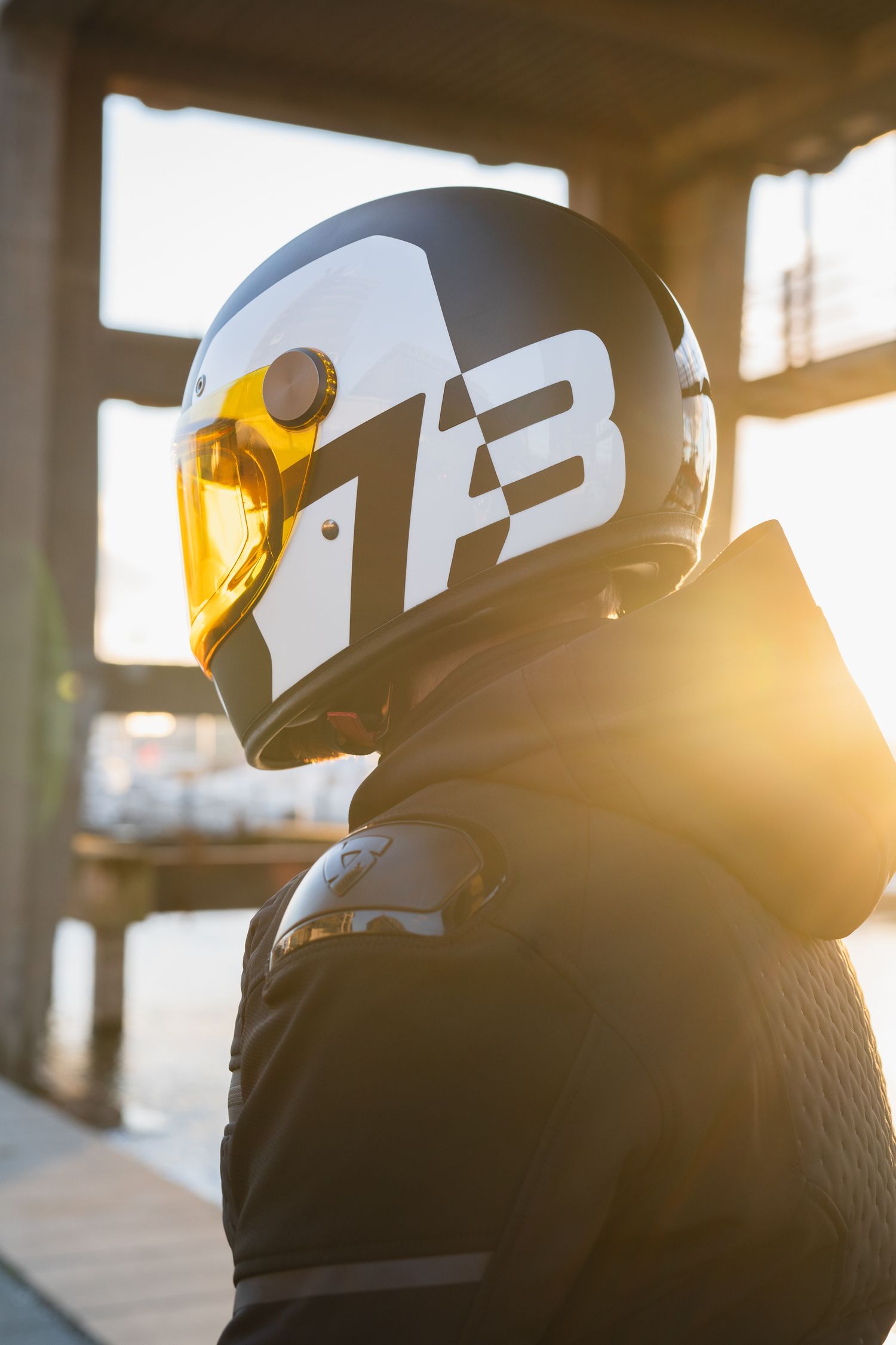 Electric motorcycle silhouetted against golden sunset light in urban setting.