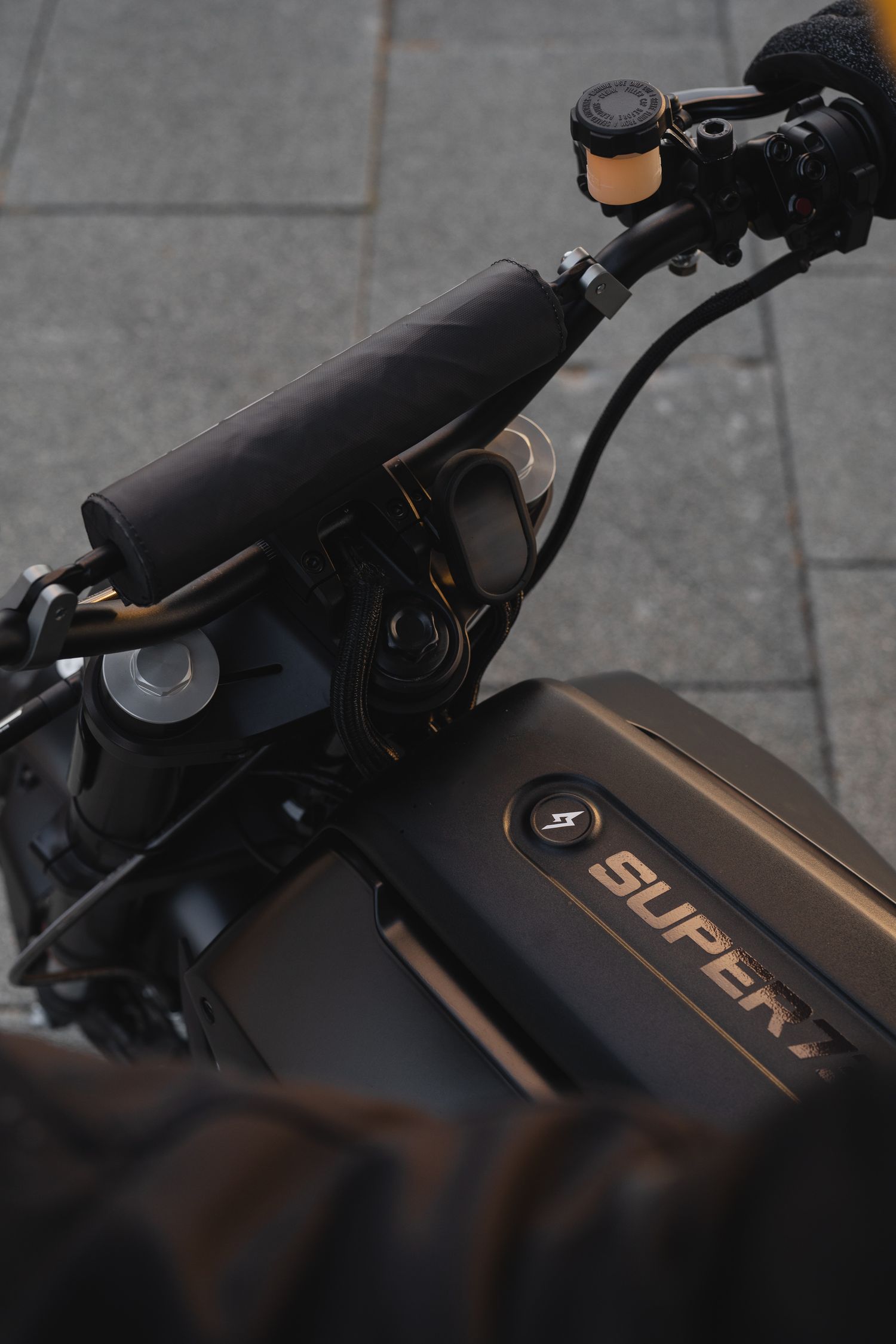 Detail shot of black motorcycle handlebars with copper-colored accents.
