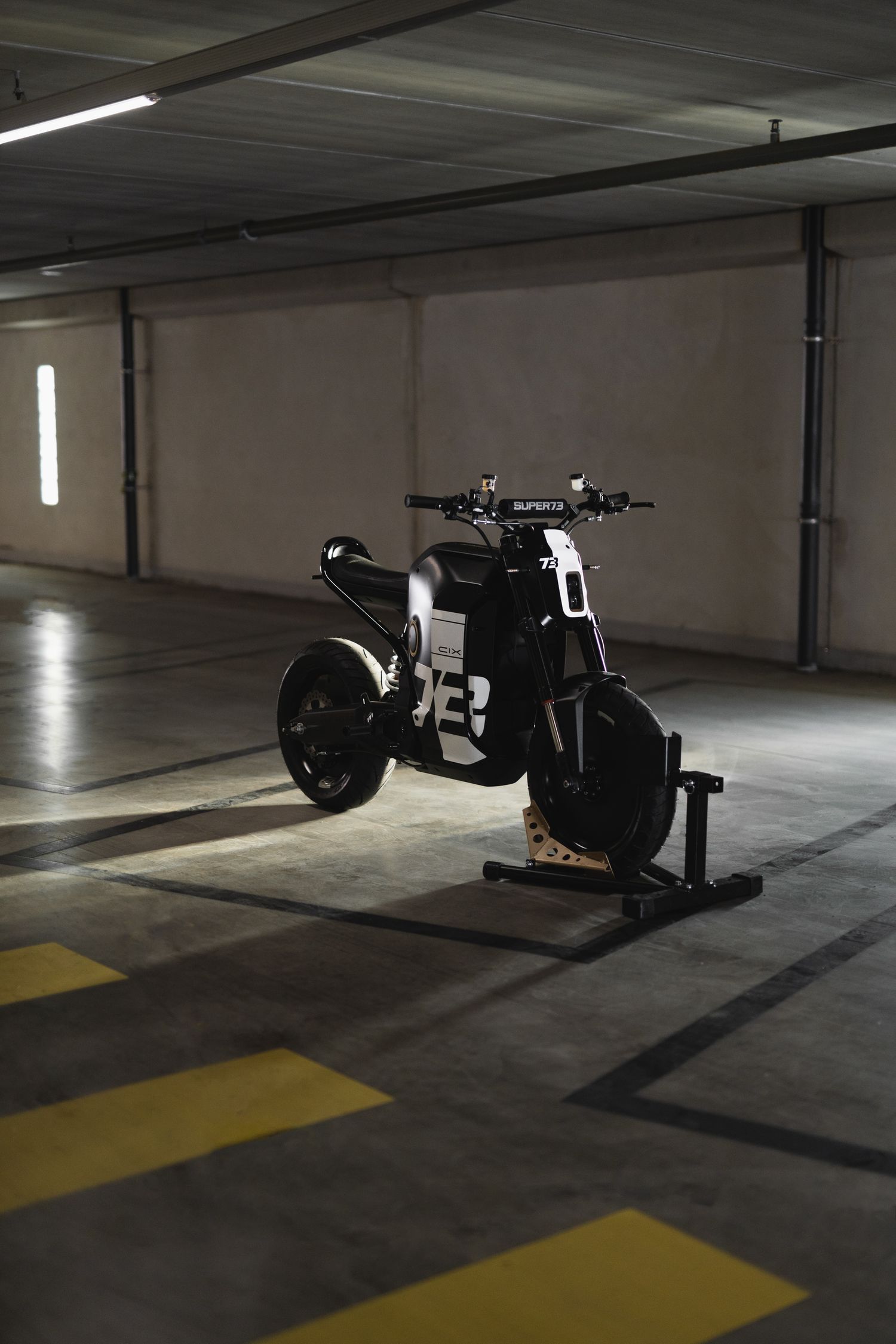 Custom black motorcycle displayed in empty parking garage with yellow floor markings.