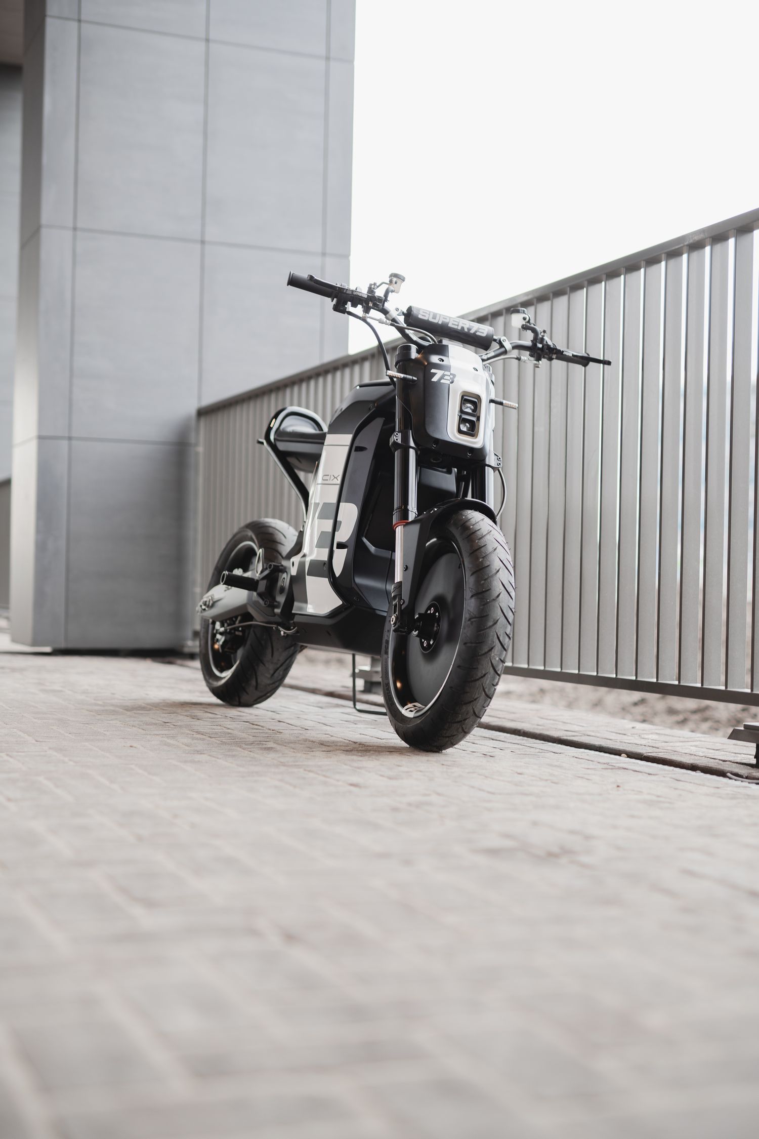 Sleek black electric motorcycle with minimalist design parked against a white wall.