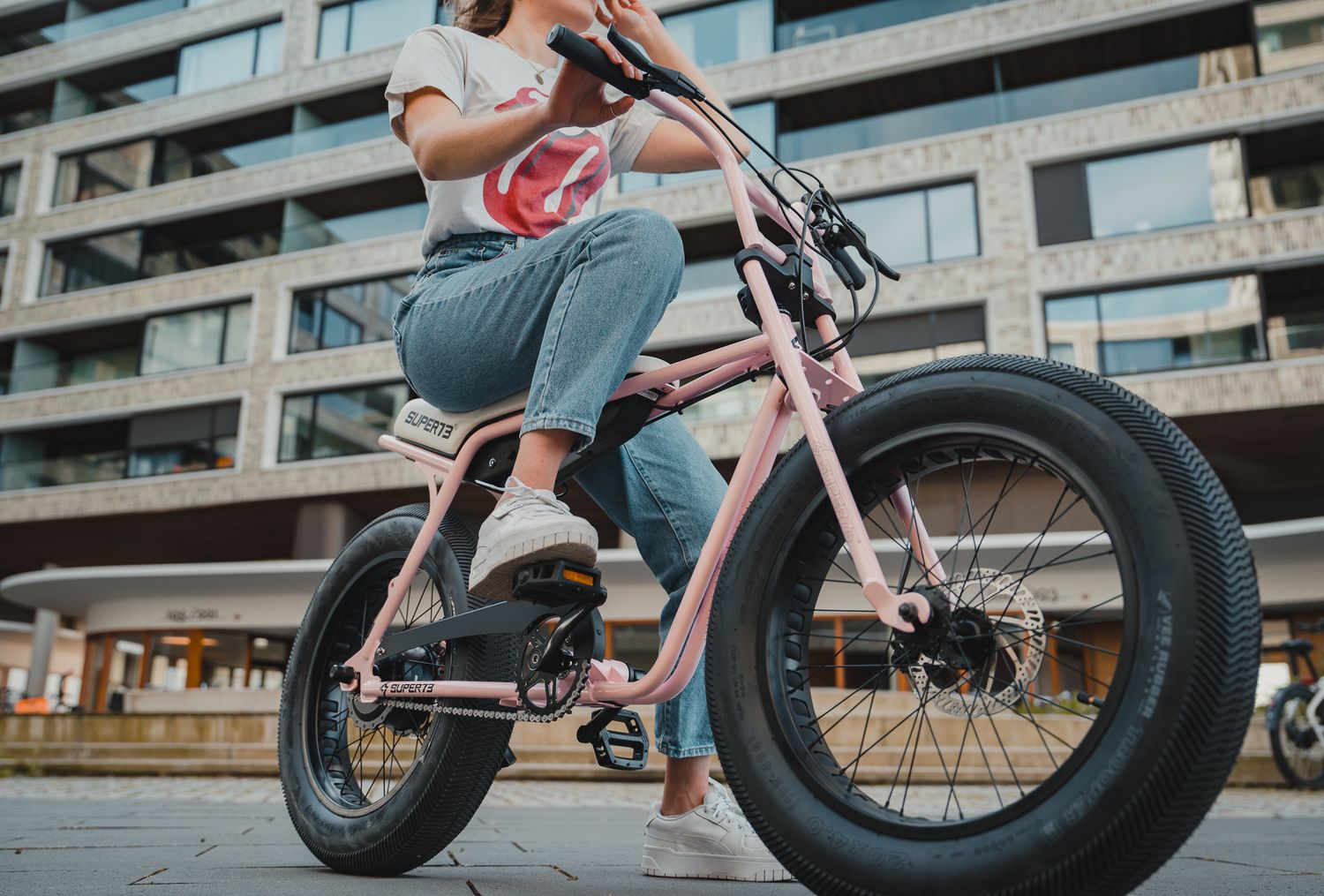 Electric bikes parked in front of a modern apartment building with geometric architecture.