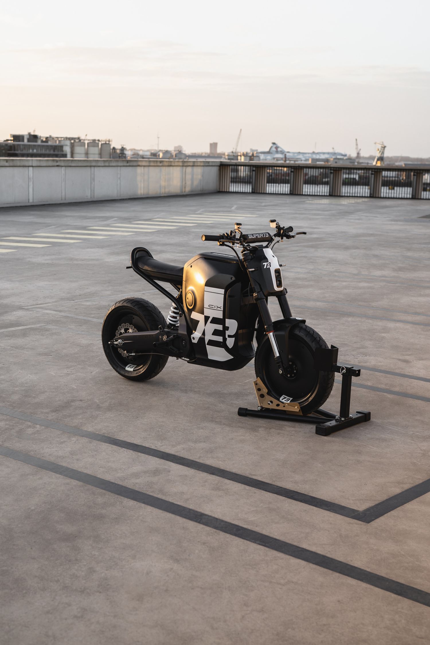 Sleek black custom motorcycle with number 23 displayed on concrete rooftop.