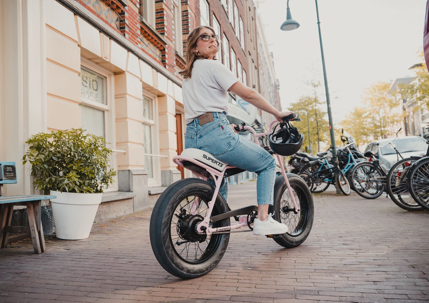 Custom motorcycles parked along urban street with brick buildings.