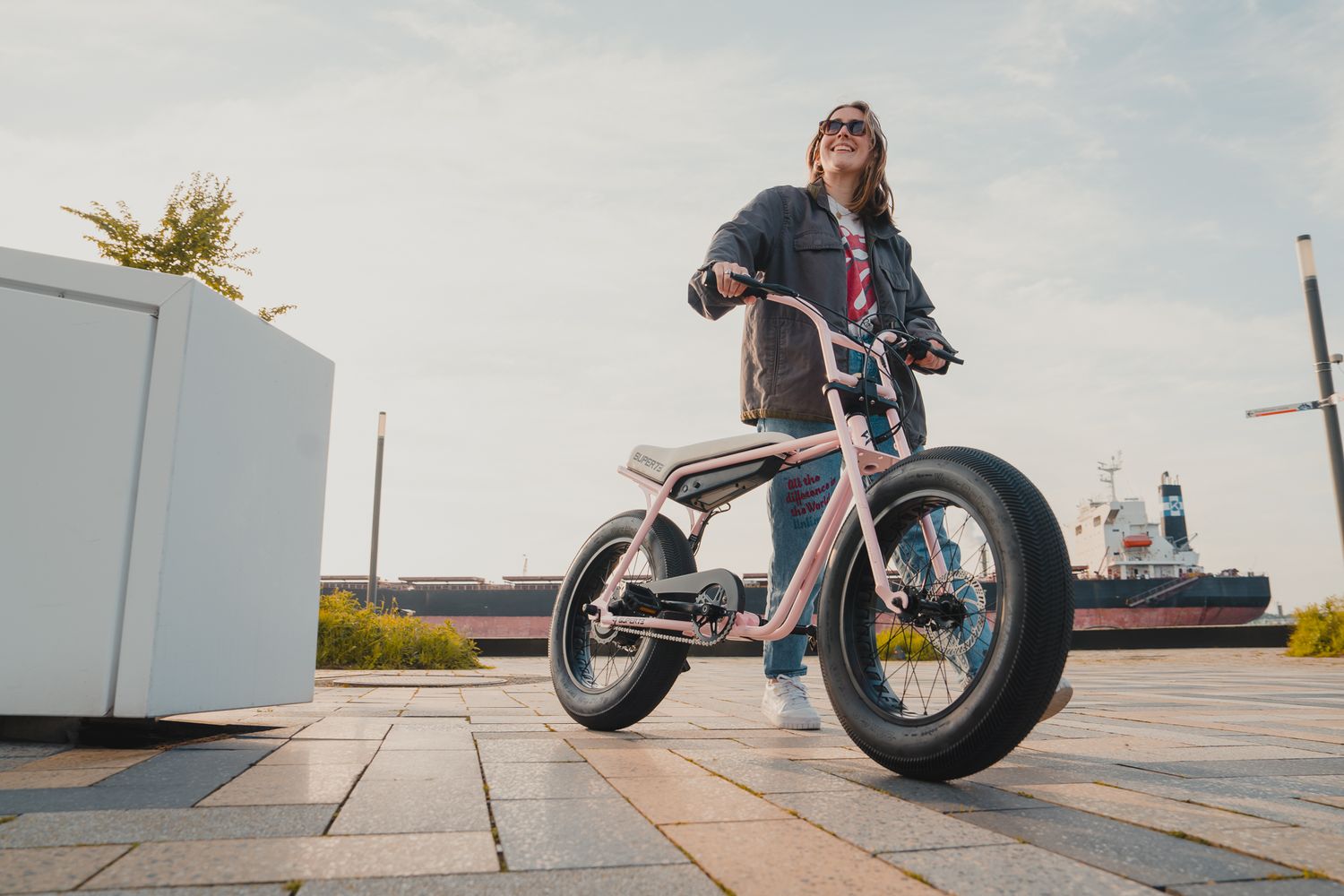 Electric bikes positioned along waterfront path with scenic harbor views.