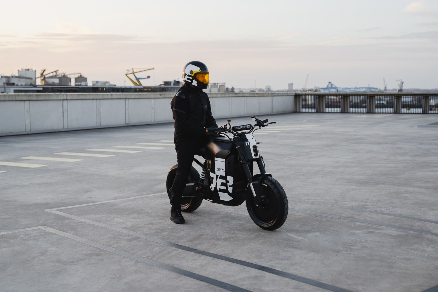 Custom motorcycle parked on empty rooftop parking lot during golden hour.