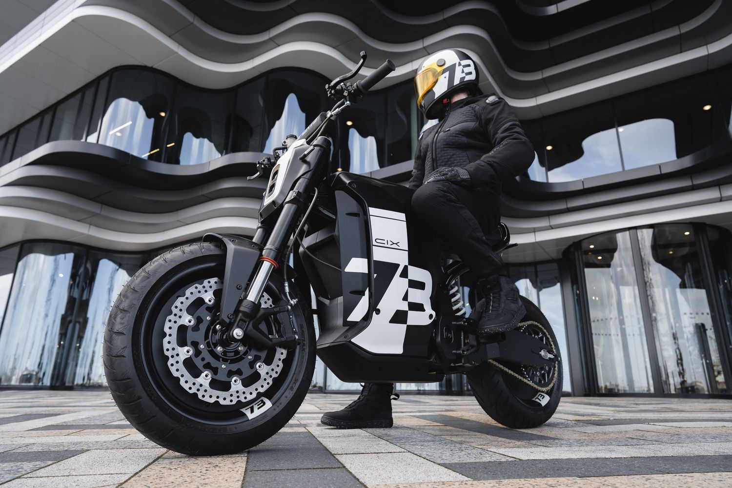 Close-up details of black motorcycle wheels and suspension components against dark background.