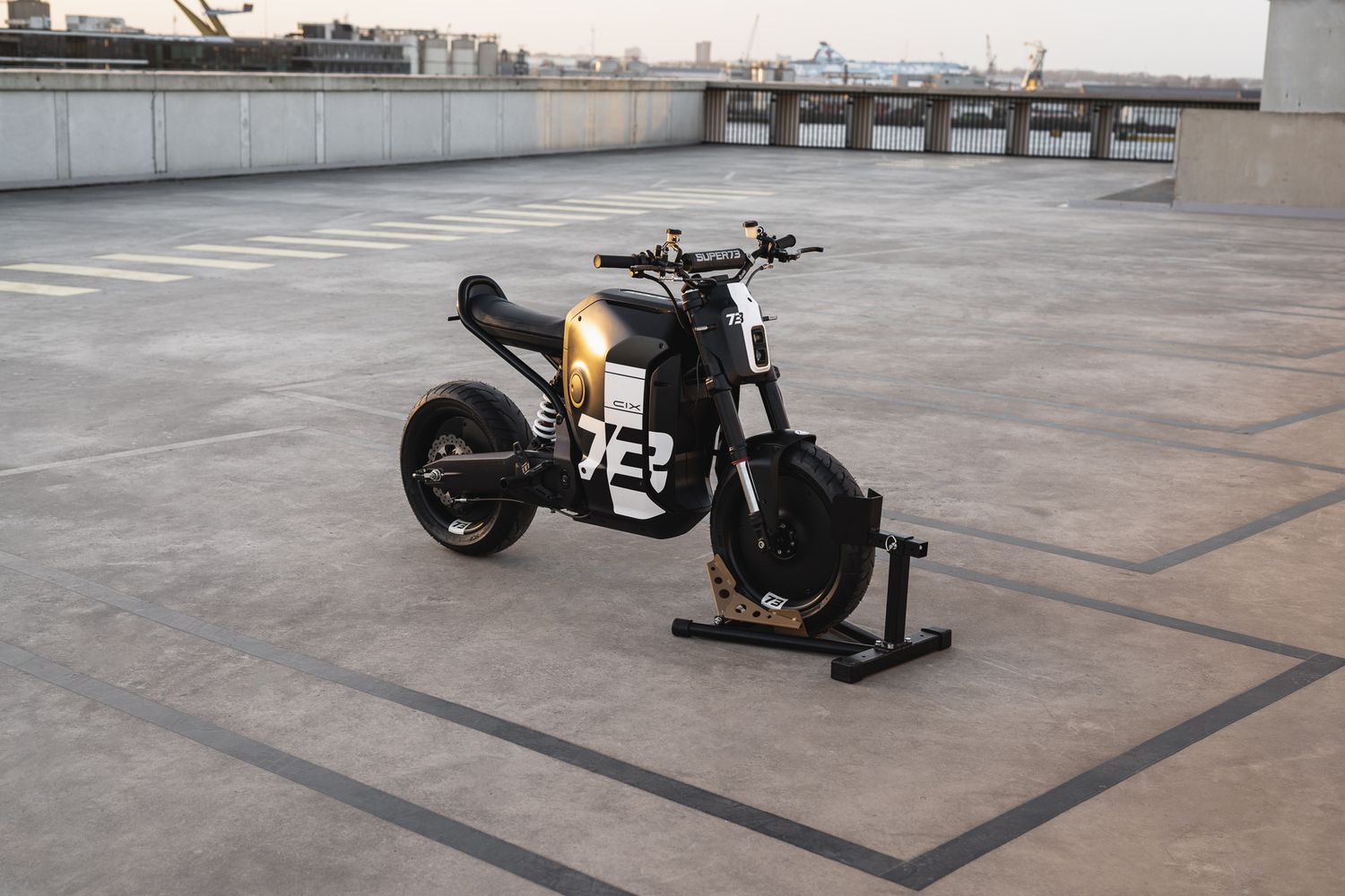 Black motorcycle with number 23 positioned on open rooftop with city skyline in background.