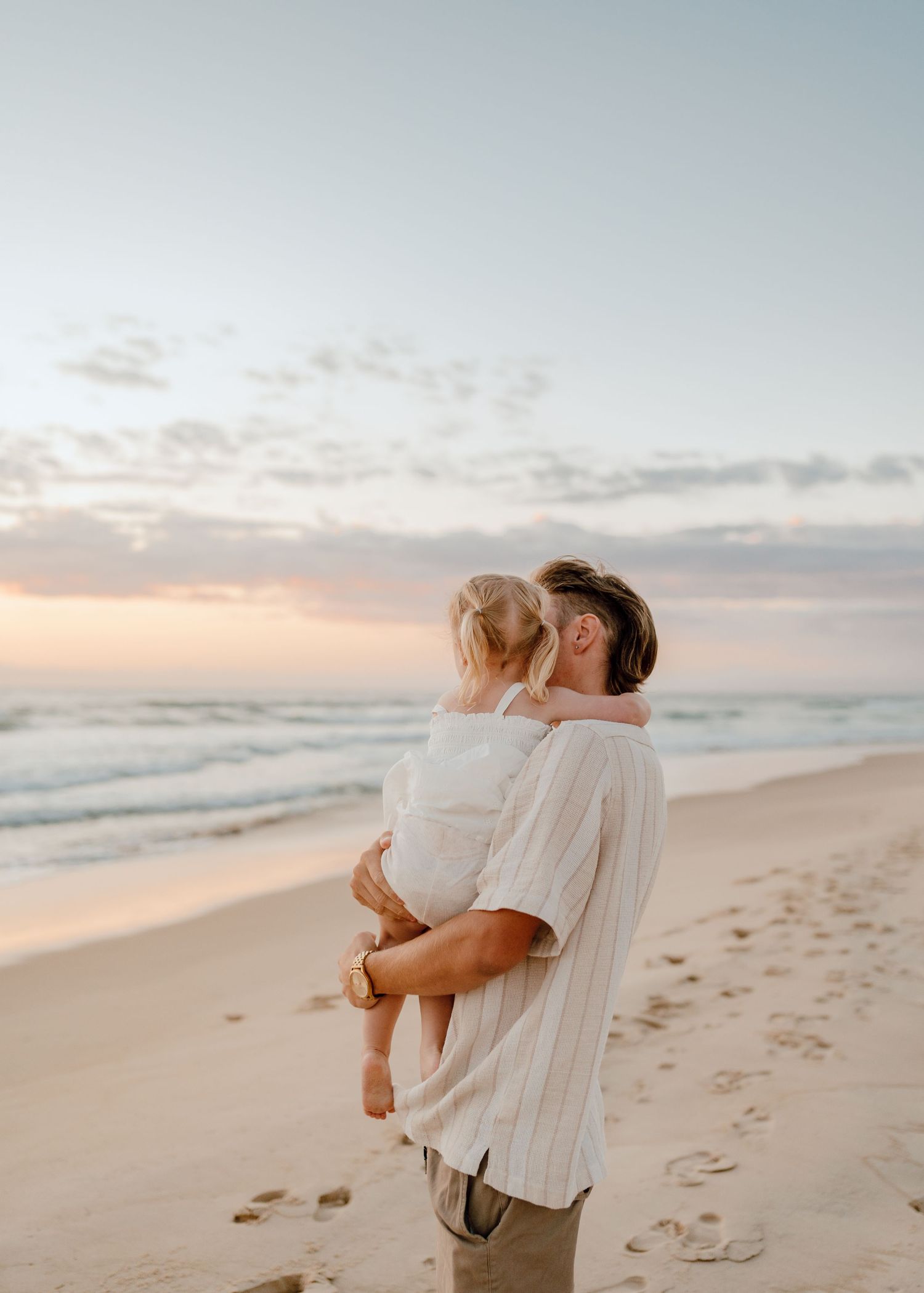 A tender moment between parent and child on a beach at sunset.
