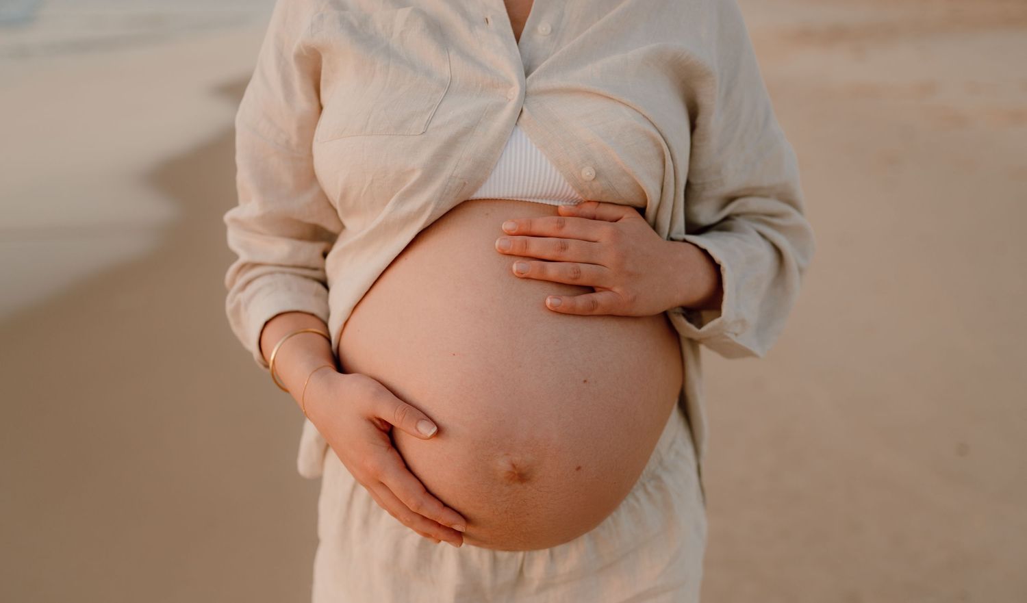 Close-up maternity photography showcasing the baby bump in soft indoor lighting.