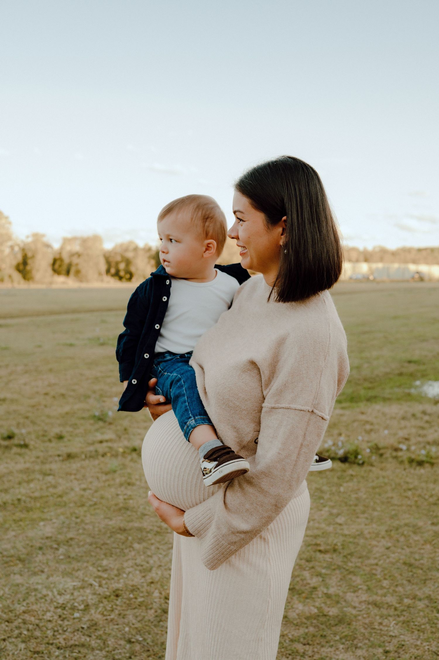 Mother and child sharing tender moment in field at sunset.