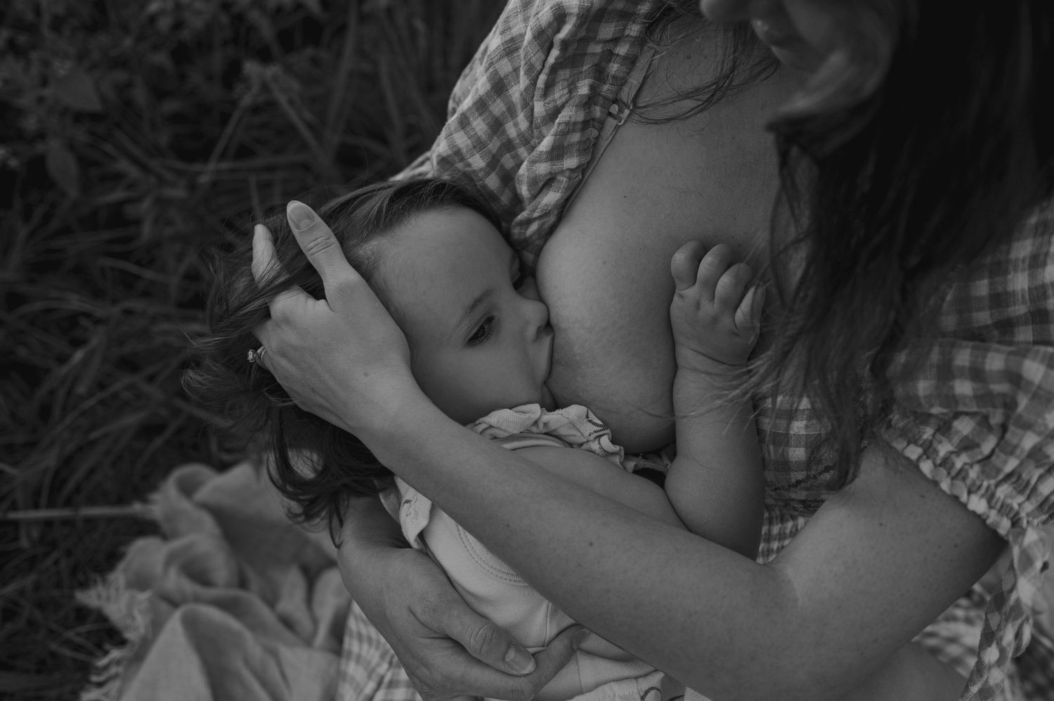 A series of black and white photographs showing tender moments of a parent bottle feeding their baby.