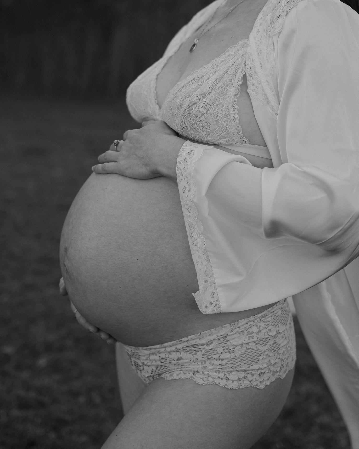 Black and white maternity photo series showing a pregnant woman's belly from different angles in lace clothing.