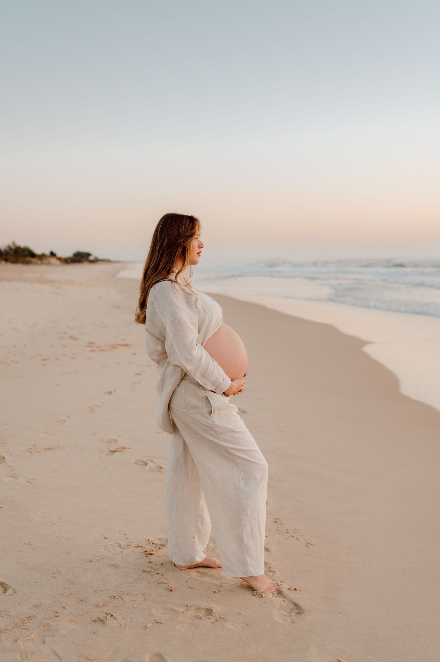 Elegant maternity photos captured on a pristine beach during golden hour.