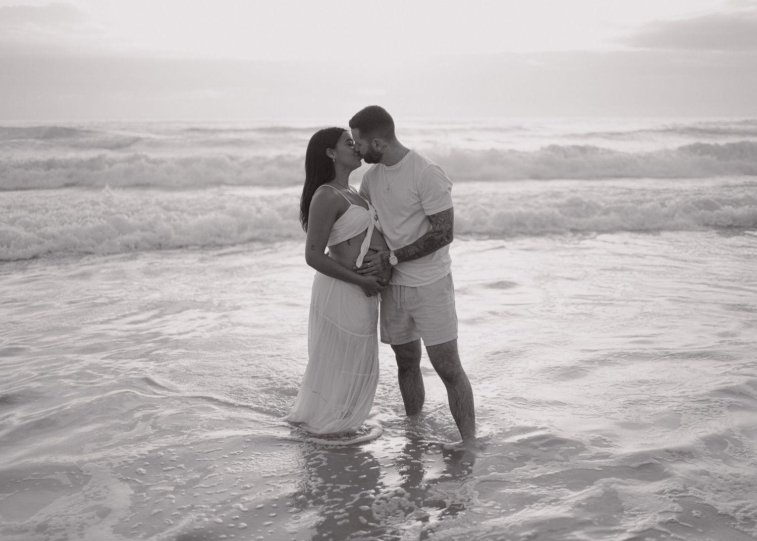 A romantic black and white photo sequence shows a couple embracing and playing in the ocean waves at the beach.