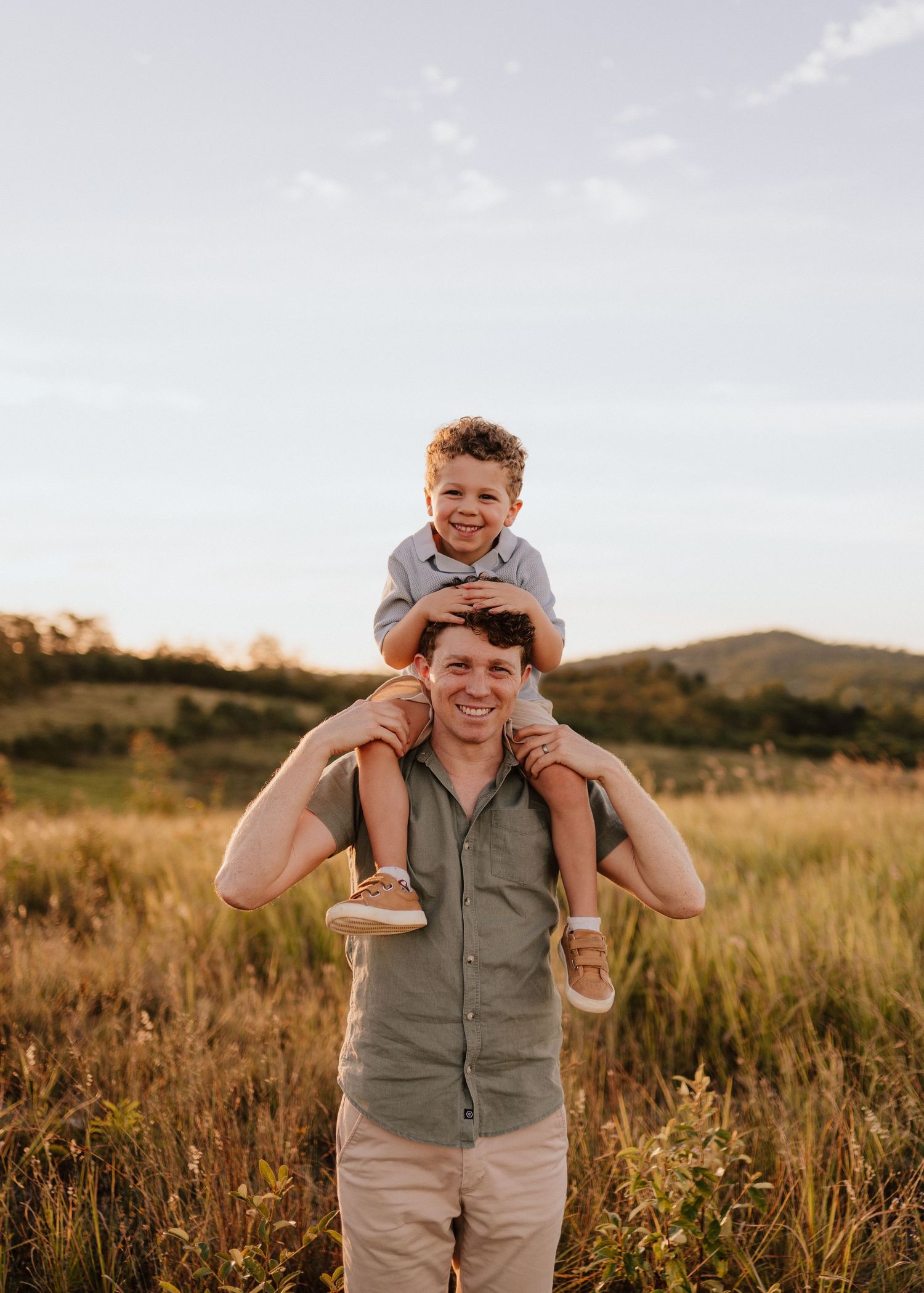 A playful family moment captured in a golden field at sunset with matching grey outfits.