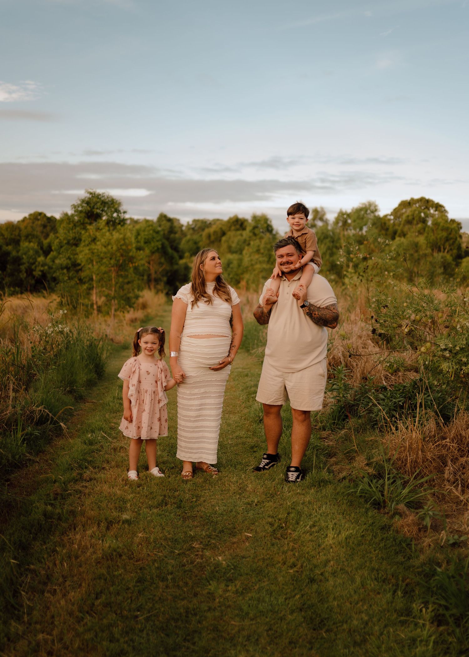 A group walks together along a grassy path through a field at sunset during a golden hour photoshoot.