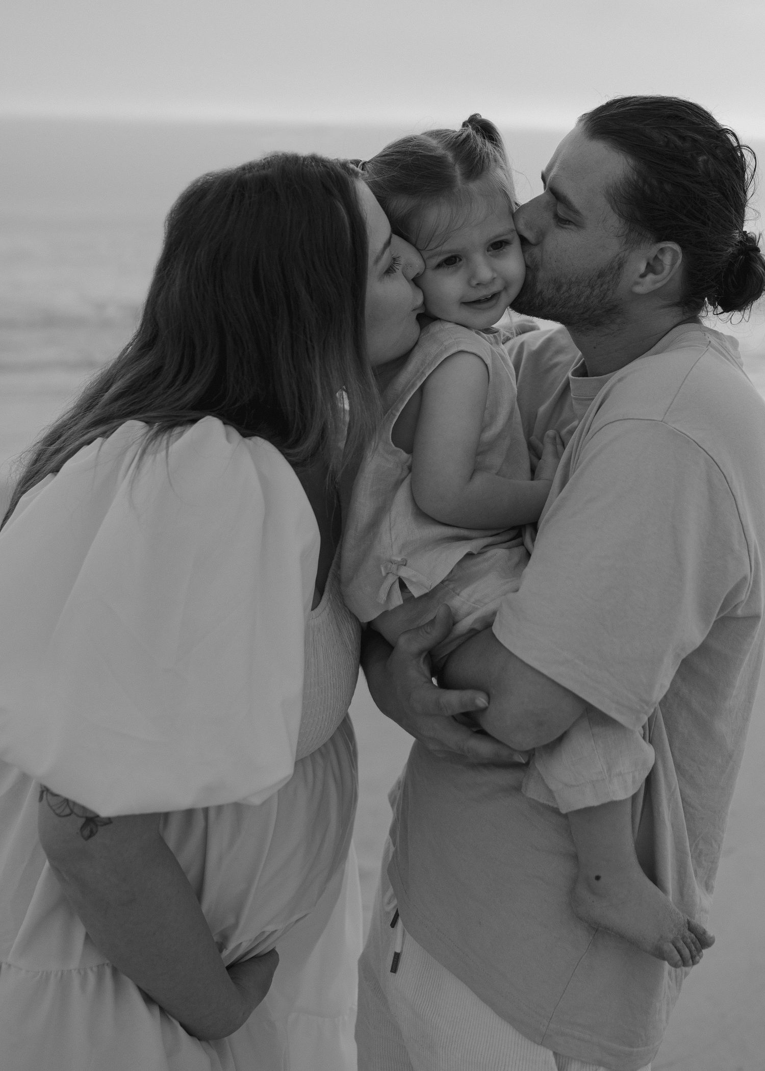 A series of black and white romantic photos showing tender moments between a couple embracing on the beach.