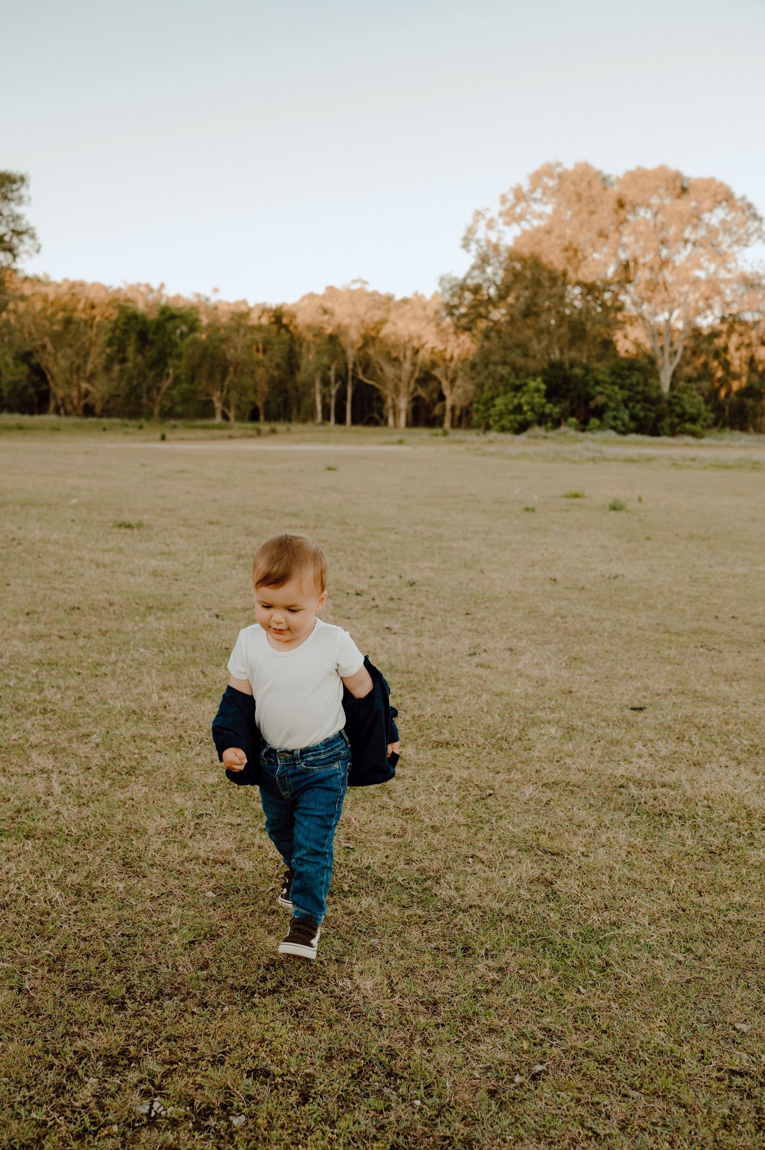 Small child running and playing freely in a grassy field during golden hour.