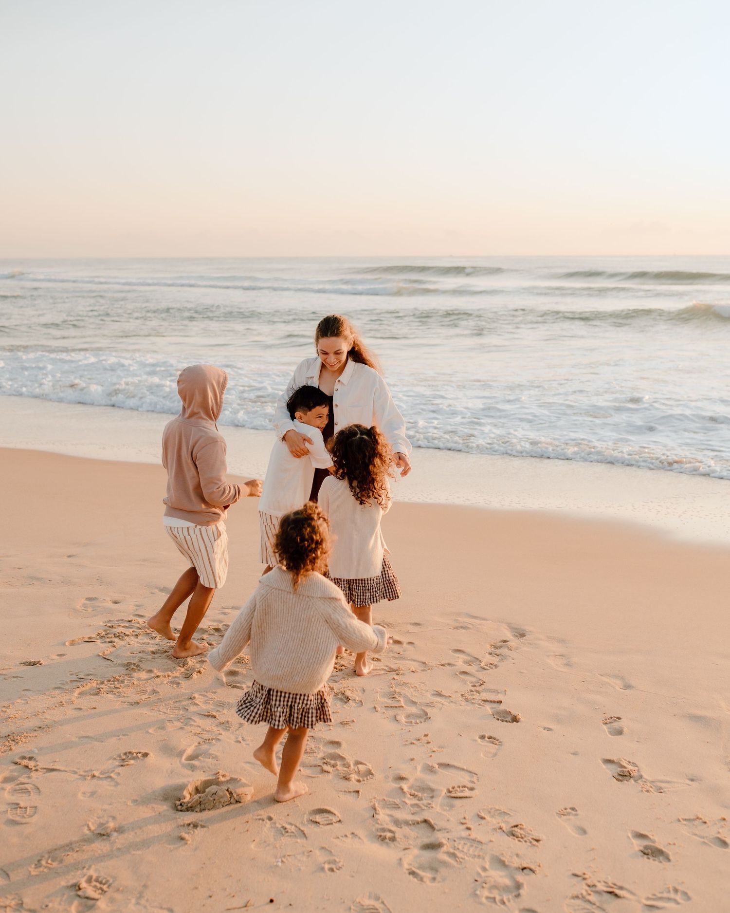 Group playing together on sandy beach during golden hour.