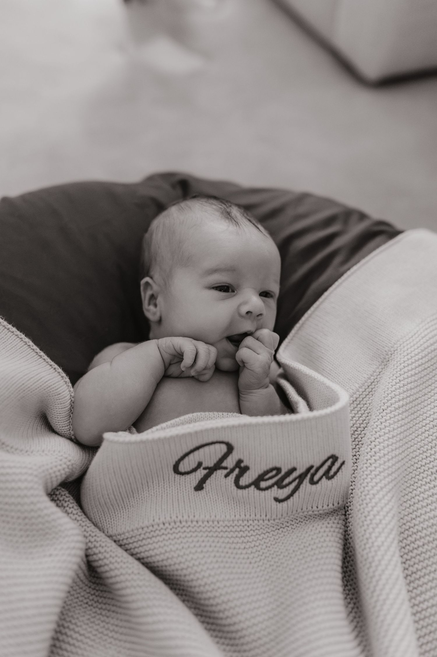 Black and white photo of newborn baby Freya wrapped in a personalized knit blanket.
