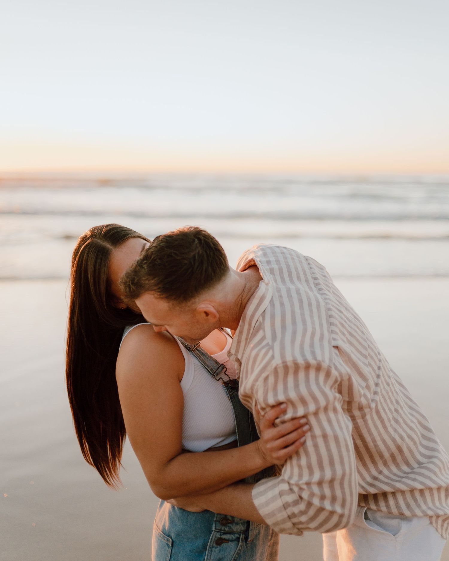 A couple shares intimate moments on the beach during sunset.