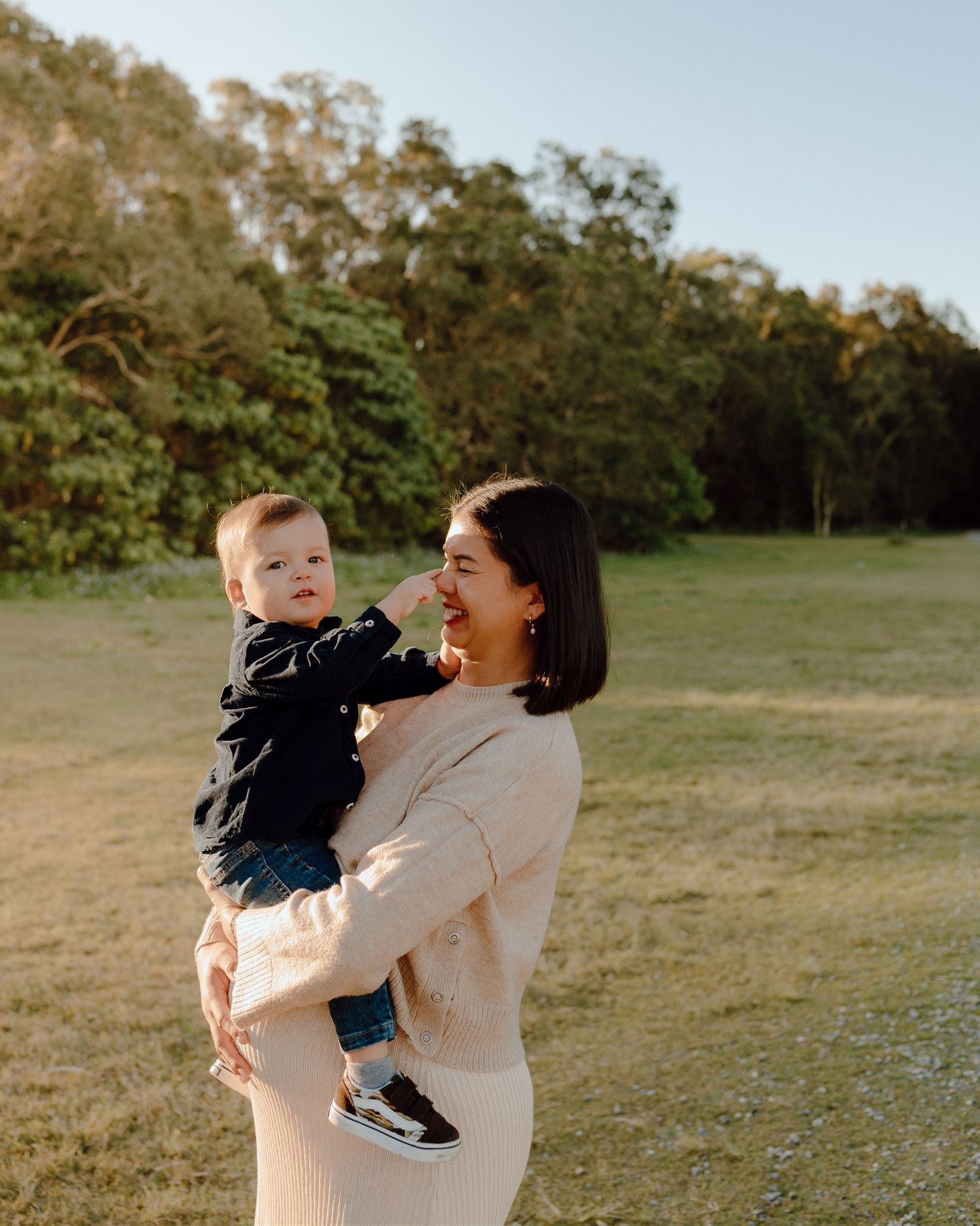 Joyful interaction between parent and child in a sunny outdoor field setting.