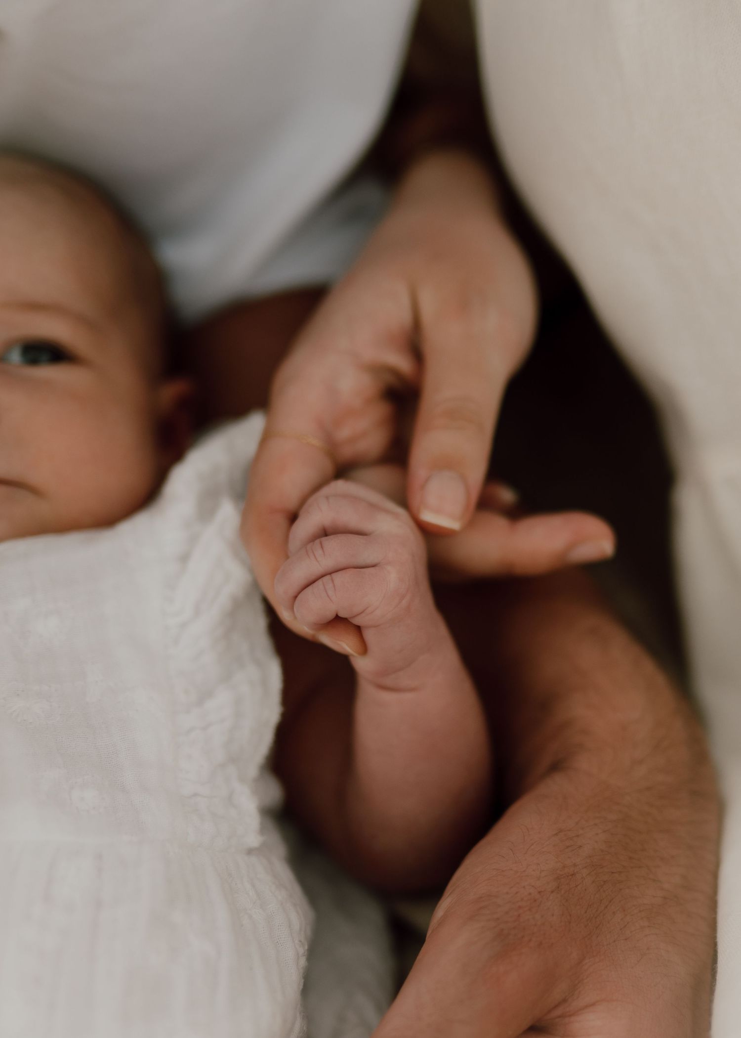 Close-up detail of tiny baby fingers being held with care and love.