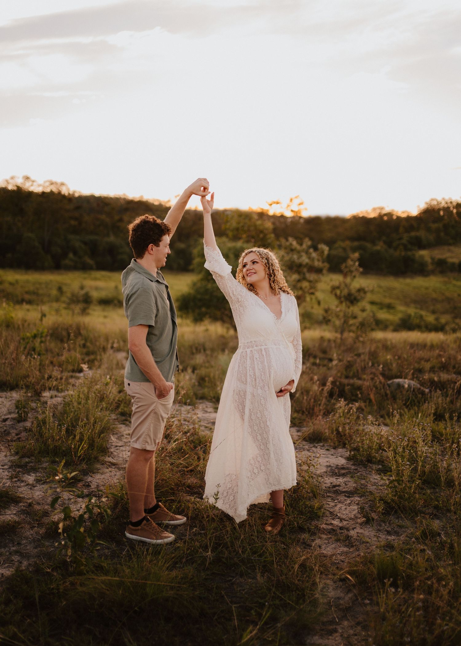 A couple dances together in a golden field at sunset creating a romantic silhouette against the warm evening sky.