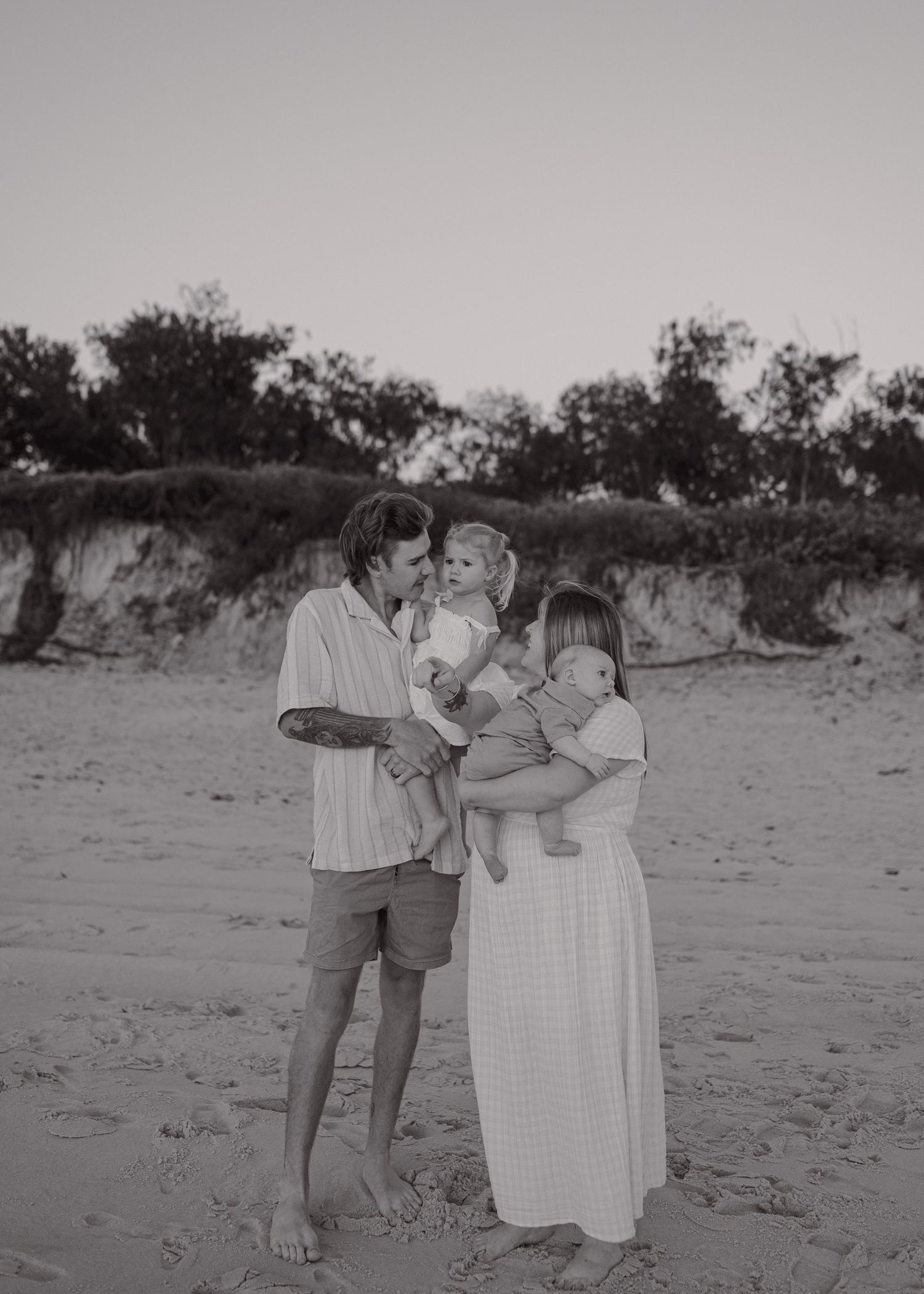 Black and white photo of family sharing tender moments on the beach.