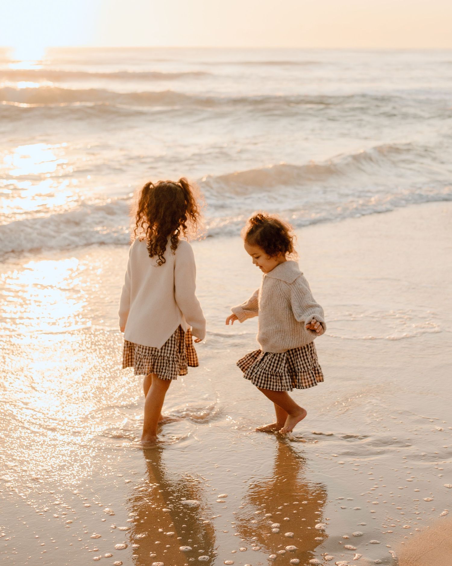 Two people splashing in ocean waves during golden sunset.